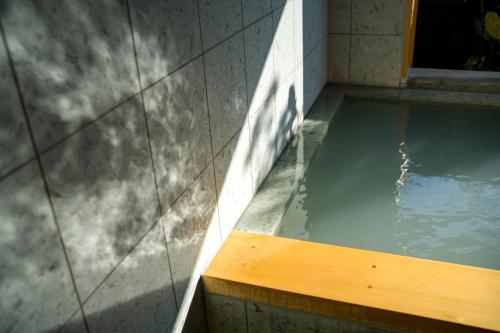 a pool of water with a wooden bench in a building at 宿坊　心月 in Arita