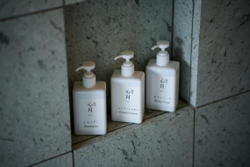 three white bottles on a wall in a bathroom at 宿坊　心月 in Arita