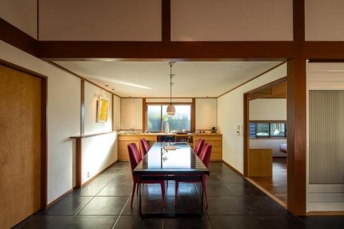 a dining room with a table and red chairs at 宿坊　心月 in Arita