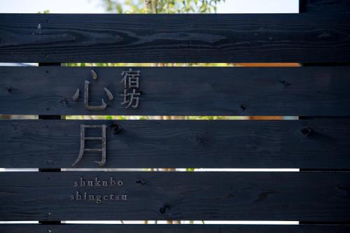 a wooden bench with a sign that says shimura istg at 宿坊　心月 in Arita