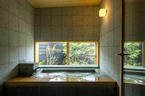 a room with a tub with a window in it at 宿坊　心月 in Arita