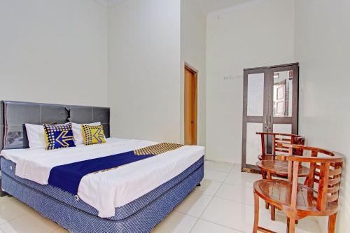 een slaapkamer met een bed, een stoel en een raam bij SPOT ON 92926 Guest House Cemara 1 Syariah in Brebes
