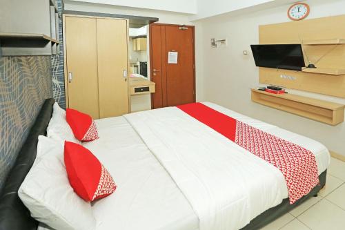 una camera da letto con un letto con cuscini rossi e una TV di Capital O 92971 Pelangi Residence a Tangerang