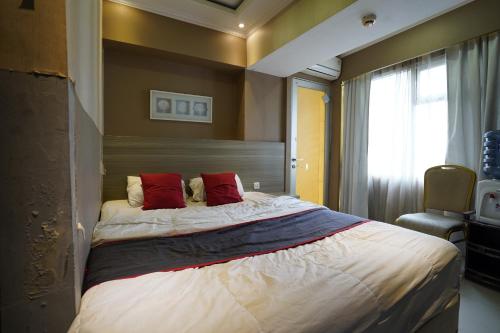 een slaapkamer met een groot bed met 2 rode kussens bij Collection O 92981 Apartemen The Jarrdin By Gold Suites Property in Bandung
