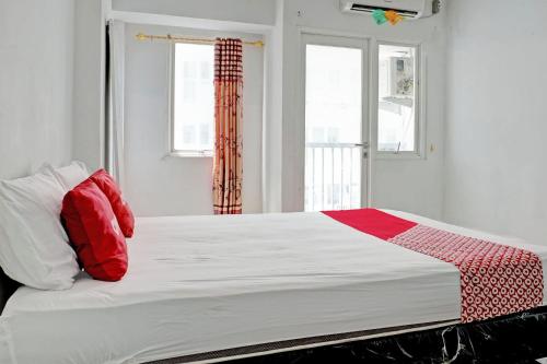 Bett mit roten und weißen Kissen in einem Zimmer in der Unterkunft Collection O 92959 Apartement Sentraland Karawang By AT Room in Karawang