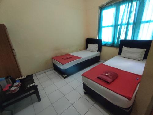 a room with two beds and a table and a window at OYO 93048 Hotel Puri Mandiri in Purworejo