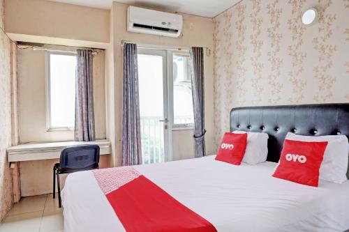 a bedroom with a bed with two red pillows at Collection O 92967 Apartement Sentraland Karawang By Rda Living in Jaken 1