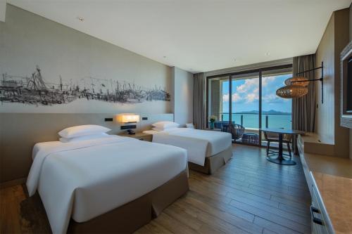 a hotel room with two beds and a table at DoubleTree by Hilton Shanwei in Shanwei