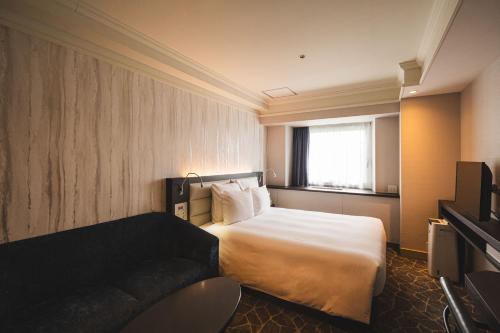 a hotel room with a bed and a couch at ANA Crowne Plaza Matsuyama by IHG in Matsuyama