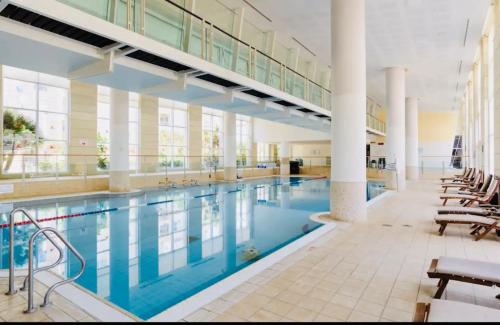 una gran piscina en un edificio con sillas y mesas en Awesome 2BR/2Bath with Pool and Gym en Herzelia 