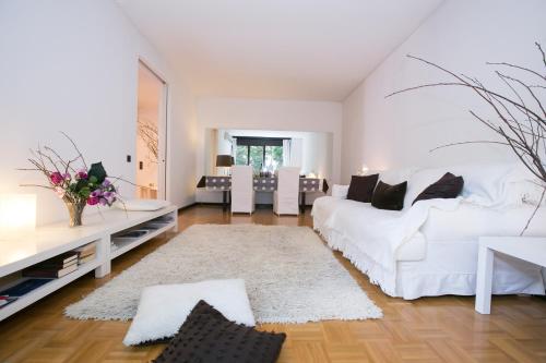 a white living room with a white bed and a table at Lugano Luxury - Happy Rentals in Lugano