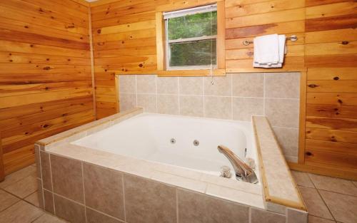 a bath tub in a bathroom with wooden walls at Big Bear Retreat in Sevierville