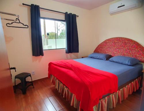 a bedroom with a bed with a red blanket and a window at 300m-da Av das Cataratas- Ar Condicionado - Estacionamento Privado in Foz do Iguaçu