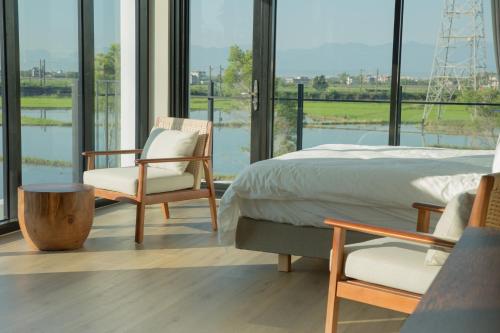1 dormitorio con cama, sillas y ventana grande en Golden Harvest Homestay, en Toucheng