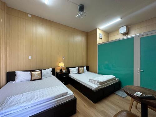 um quarto de hotel com duas camas e uma mesa e uma secretária em OYO 1199 Dung Quyen Hotel em Da Nang