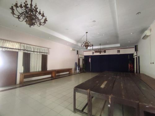 a large room with a wooden table and a stage at Capital O 93024 Hotel Ganesha in Purworejo
