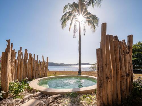 uma cerca de madeira com uma banheira de hidromassagem em frente a uma palmeira em Bleu MATHIS Gili Asahan em Gili Asahan