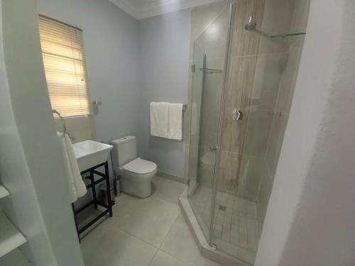 a bathroom with a shower and a toilet and a sink at REALJOY GUEST SUITES in Centurion