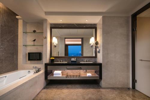 a bathroom with a tub and a large mirror at Hilton Changzhou in Changzhou