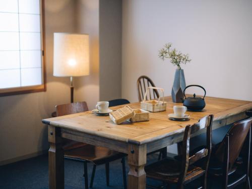 a wooden table with chairs and a lamp and a table with cups at MIMARU SUITES Kyoto Shijo in Kyoto