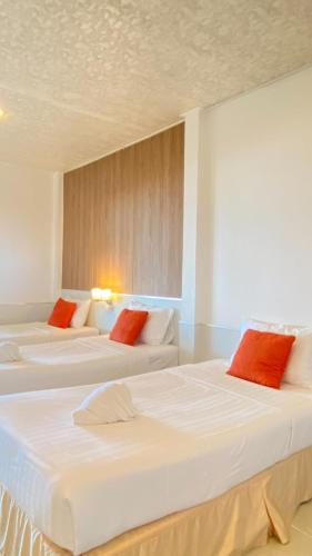 two white beds in a room with red pillows at Laemsing Natural Beach Resort in Ban Pak Nam