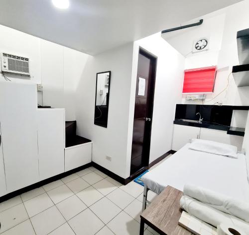 Cette chambre blanche comprend un lit et une table. dans l'établissement Dasma Lofts Hotel near Dela Salle Dasma, à Dasmariñas