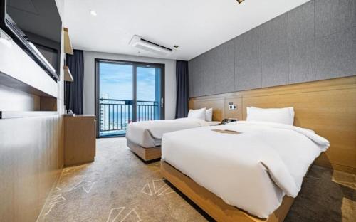 a hotel room with two beds and a large window at Sea Cruise Hotel in Sokcho