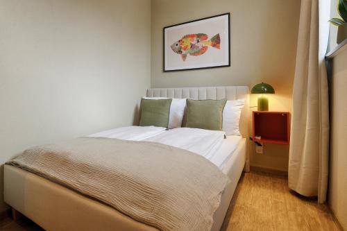 1 dormitorio con 1 cama grande con sábanas blancas y almohadas verdes en Ferienwohnung Fischzucht - Sauna, große Dachterrasse, 3 Schlafzimmer - by homekeepers, en Würzburg