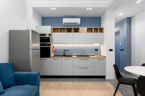 uma cozinha com armários brancos e uma parede azul em [Centro Torino] Elegante e Moderno Bilocale em Turim