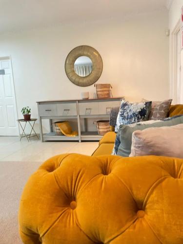 a living room with a yellow couch and a mirror at Ambré Guesthouse in Francistown