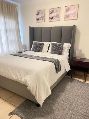 1 dormitorio con 1 cama grande y cabecero gris en Ambré Guesthouse, en Francistown