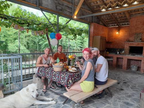 un grupo de personas sentadas en una mesa con un perro en Zaalis wine cellar, en Vani