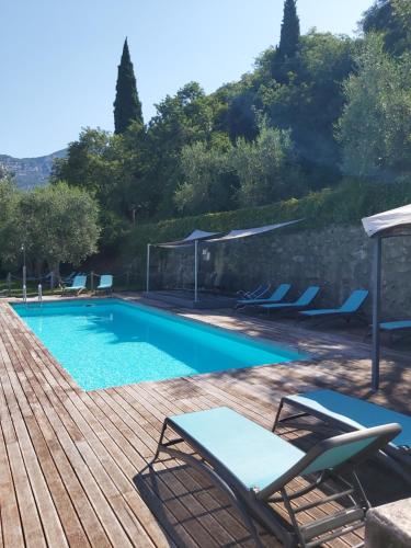 una piscina con sedie e una terrazza in legno di Casa Romani Lake Apartments a Torbole