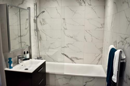 ein weißes Bad mit einem Waschbecken und einer Dusche in der Unterkunft R V Properties Luxury Suites 21 & 23 in Hemel Hempstead