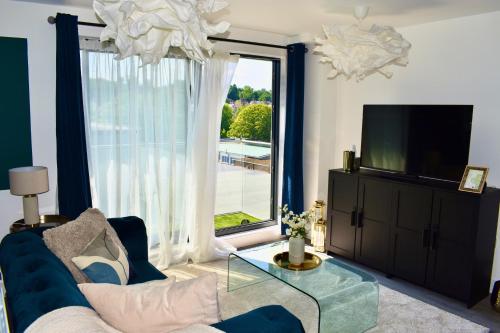 ein Wohnzimmer mit einem blauen Sofa und einem großen Fenster in der Unterkunft R V Properties Luxury Suites 21 & 23 in Hemel Hempstead