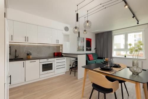 uma cozinha com armários brancos e uma mesa e cadeiras em Warsaw Piaseczno Stylish Apartment with Parking by Renters em Piaseczno