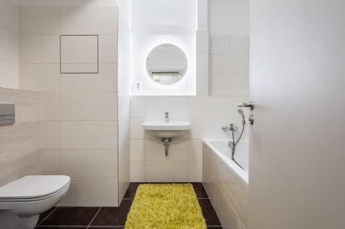 a bathroom with a toilet and a sink and a yellow rug at AuriApartments Libeň nový byt 1kk s garáží in Prague