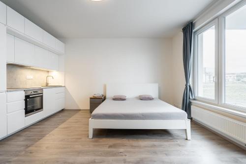 a white bedroom with a bed and a large window at AuriApartments Libeň nový byt 1kk s garáží in Prague