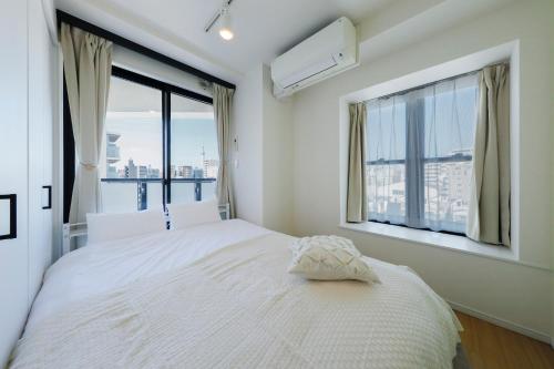a bedroom with a white bed and a large window at Kiyosumi SOHO in Tokyo