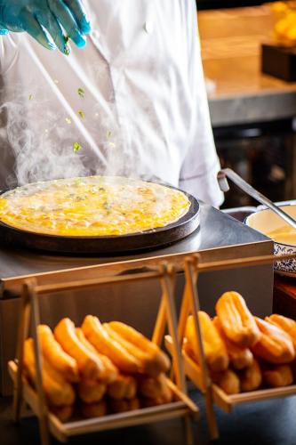a chef is preparing a pizza and a tray of donuts at Conrad Tianjin in Tianjin