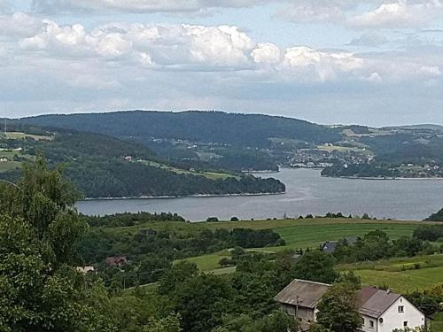 a view of a river with a house in the foreground at Domek nad jeziorem Rożnowskim - Gródek Nad Dunajcem in Gródek Nad Dunajcem