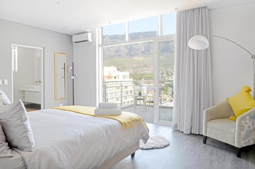 ケープタウンにあるNaomi - Designer Penthouse in the Heart of Cape Townの白いベッドルーム(ベッド1台、椅子、窓付)