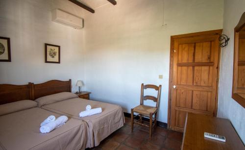 1 dormitorio con 2 camas, silla y puerta en Casa rural el Carmen, en Prado del Rey