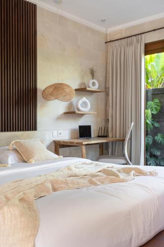 a bedroom with a bed and a desk with a laptop at Designer Studio Emy Sanur in Sanur