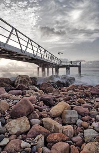 a bridge on a beach with rocks and the water at Apartamento a 200 metros de la playa de arena Les Cases en Xilxes - Castellón in Chilches