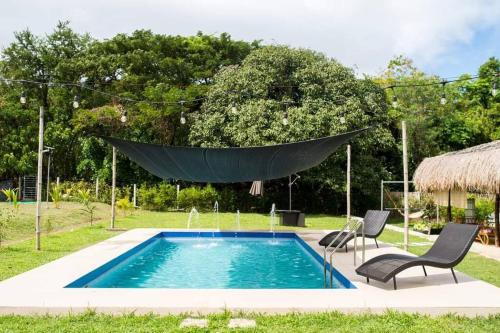 a hammock hanging over a swimming pool with two chairs at Entire farm place w/ 2 casitas & dipping pool in Lubo