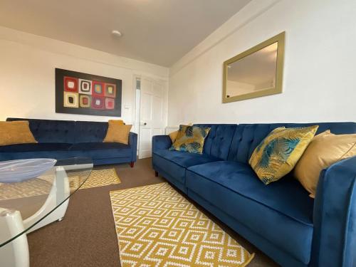 a living room with a blue couch and a table at Plymouth Central Apartments in Plymouth