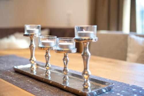 three wine glasses on a tray on a table at Ferienwohnung 73 - Smaragd in Wald im Pinzgau