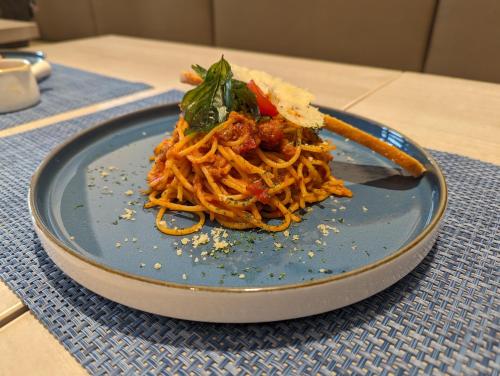 a blue plate with spaghetti on a table at Fairfield by Marriott Jakarta Soekarno-Hatta Airport in Tangerang