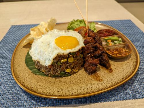 a plate of food with a fried egg on top at Fairfield by Marriott Jakarta Soekarno-Hatta Airport in Tangerang